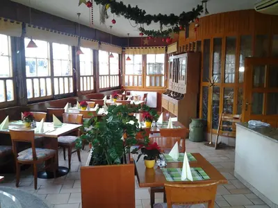 a restaurant with wooden tables and chairs and windows at Guest House Arvaj in Kranj