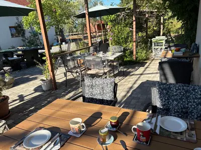 a wooden table with plates on it on a patio at Lipizzaner Lodge Guest House in Postojna