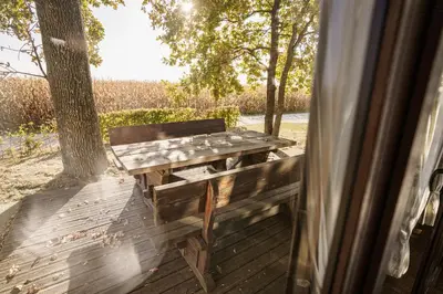 a wooden bench sitting on a deck with trees at Panonska Vas Villas in Moravske Toplice