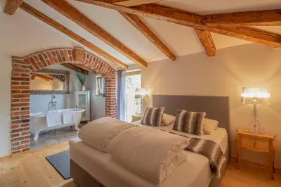 a bedroom with a bed and a bathroom with a tub at Residence Apolonija Guest House in Sežana
