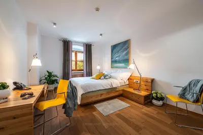 a bedroom with a bed with a desk and yellow chairs at Vila Vipolže - Rooms & J. Suites in Vipolže