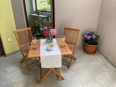 a table with two chairs and a vase of flowers on it at Apartma 7 - In the heart of Soča Valley in Tolmin