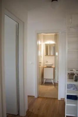 a white bathroom with a sink and a mirror at Chang Thai apartments in Ljubljana