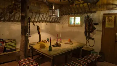 a room with a wooden table and two stools at Gozdna koča Studeno in Kočevje