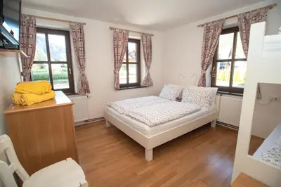 a small bedroom with a bed and two windows at Apartment Hribovc with atrium and free parking in Kranjska Gora