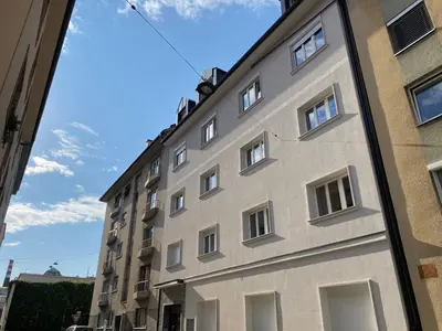 a tall building with white windows on a street at Boennium Apartments in Ljubljana