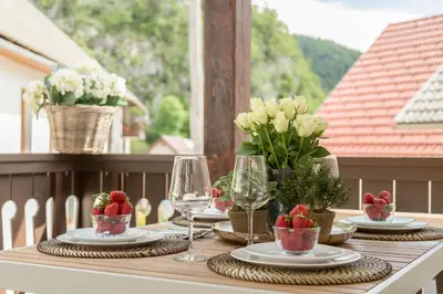 a table with plates and wine glasses on a balcony at House Bella in Bohinjska Bela
