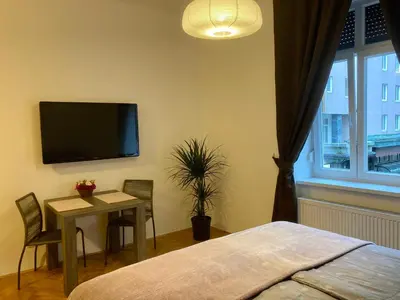 a bedroom with a table and a tv on the wall at Twix apartment in Ljubljana