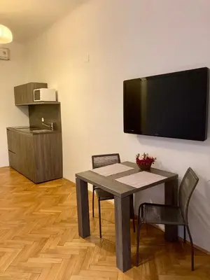a dining room with a table and chairs and a flat screen tv at Twix apartment in Ljubljana