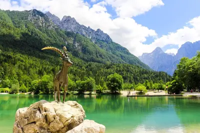a statue of a bird on a rock in front of a lake at Apartma Prisank Kranjska Gora in Kranjska Gora