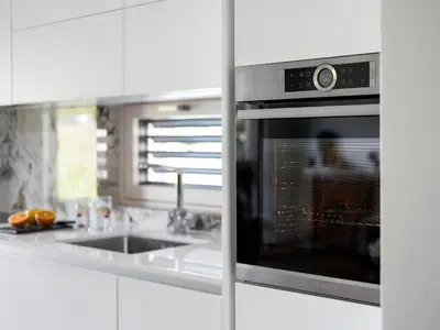 a kitchen with an oven in a white kitchen at Maison du Soleil in Kranjska Gora