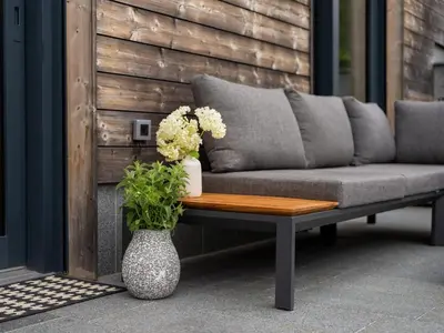 a couch and a table with flowers on a patio at Maison du Soleil in Kranjska Gora