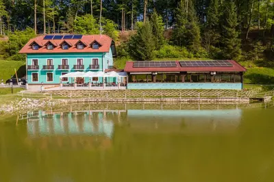 a building with solar panels on top of a lake at Penzion ob Ribniku in Podlehnik
