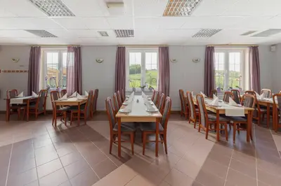 a dining room with tables and chairs and windows at Penzion ob Ribniku in Podlehnik
