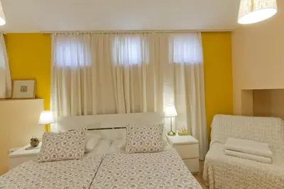 a small bedroom with a bed and a chair at City Centre Apartments in Ljubljana