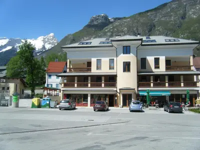 a large building with cars parked in a parking lot at Vila Bovec Sunrise apartment with balcony in Bovec