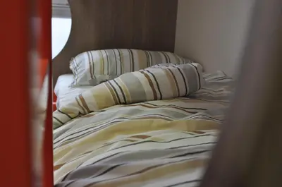 an unmade bed with two pillows on top of it at Hostel Tivoli in Ljubljana
