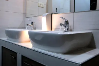 two sinks in a bathroom with two faucets at Hostel Tivoli in Ljubljana