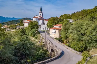 a winding road leading to a church on a hill at Panorama glamping Vipavska dolina in Dobravlje