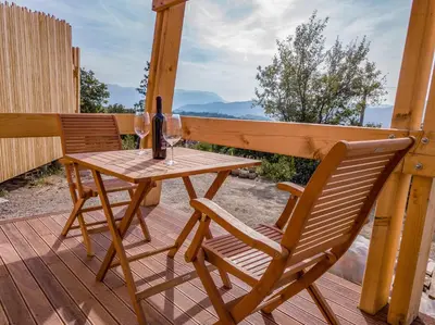 a wooden table and two chairs on a deck at Panorama glamping Vipavska dolina in Dobravlje