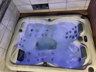 a bath tub filled with blue water in a bathroom at Apartment Mastnak - Private Wellness & Jacuzzi in Laško