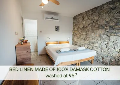 a bed in a bedroom with a stone wall at Villa Lapis in Črni Kal