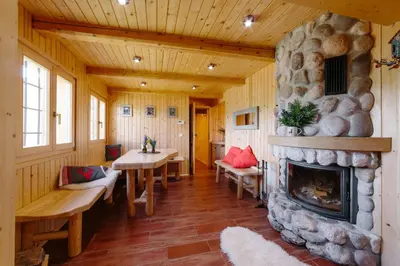 a living room with a fireplace and a table and chairs at Chalet Orlica Velika Planina in Stahovica