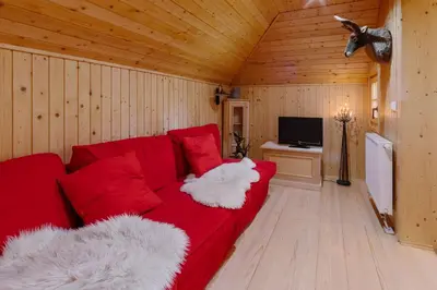 a living room with a red couch and a tv at Chalet Orlica Velika Planina in Stahovica