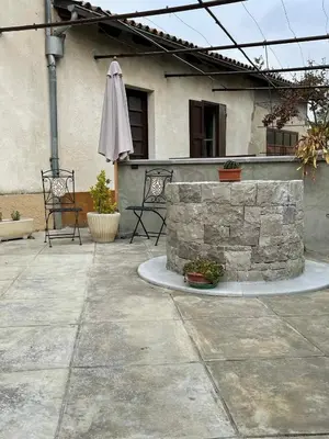 a patio with a stone wall and an umbrella at Cilka`s house, authentic homestay near Lipica in Sežana