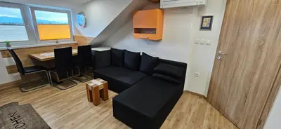 a living room with a black couch and a table at Apartma AJJA in Šenčur