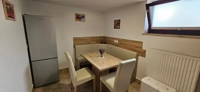 a small kitchen with a table and chairs and a refrigerator at Apartma AJJA in Šenčur