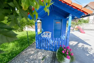 a blue shack with a bench in a yard at Guest House Bakhus in Žerjavka