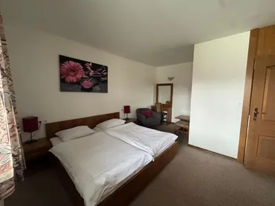 a bedroom with a white bed and a flower painting on the wall at Guest House Bakhus in Žerjavka