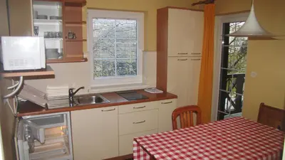 a kitchen with a sink and a table with a table cloth at Terme Olimia - Apartment Village Lipa in Podčetrtek