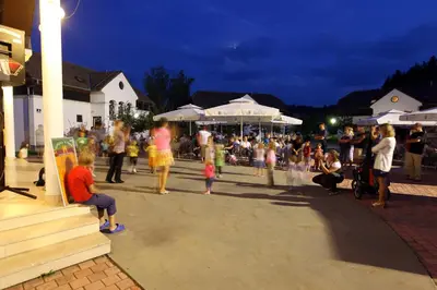 a crowd of people standing around in a street at night at Terme Olimia - Apartment Village Lipa in Podčetrtek
