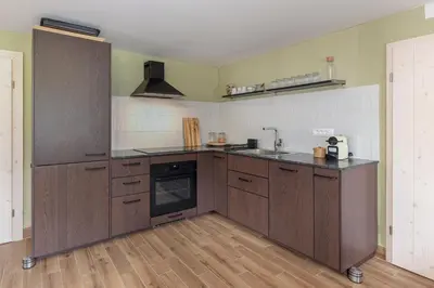 a large kitchen with wooden cabinets and a stove at Farmhouse Chalet Apartments in Bohinjska Bistrica
