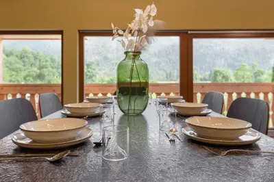 a table with plates and a vase with flowers on it at Farmhouse Chalet Apartments in Bohinjska Bistrica