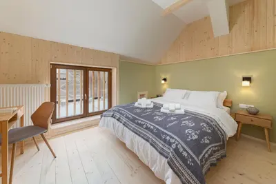 a bedroom with a bed and a desk and a window at Farmhouse Chalet Apartments in Bohinjska Bistrica
