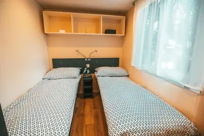 two beds in a room with a table and a window at Holiday cottage with 2 Thermal Riviera Tickets in Moravske Toplice