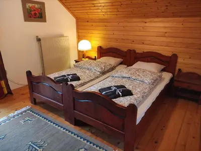 two twin beds in a room with wooden walls at Alp House in Bohinjska Bela