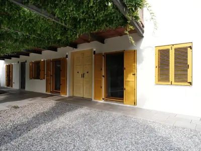 a white house with yellow doors and windows at House Wisteria in Kostanjevica na Krasu