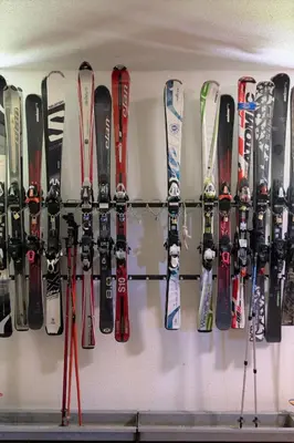 a bunch of skis and snowboards are lined up on a wall at Apartma Krvavec - cosy mountain retreat in Cerklje na Gorenjskem