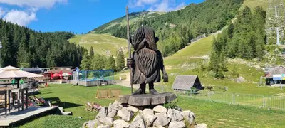 a statue sitting on top of a field with a mountain at Apartma Krvavec - cosy mountain retreat in Cerklje na Gorenjskem