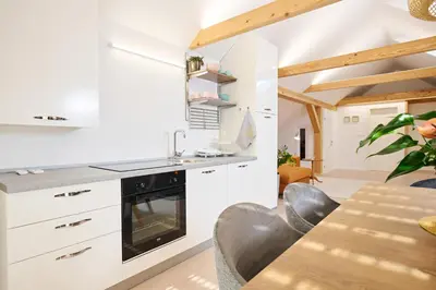a kitchen with white cabinets and a table with chairs at Apartment P42 in Slovenj Gradec