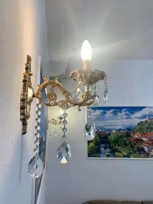 a gold chandelier hanging on a wall with a picture at Ljubljana City Center Apartment in Ljubljana