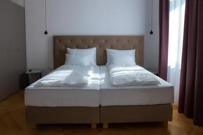 a bed with white sheets and pillows in a bedroom at Hotel Belmur in Murska Sobota