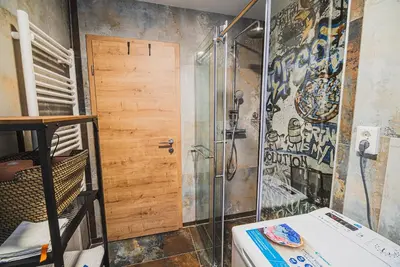 a bathroom with a shower and a wooden door at Apartment VAZATAOR with sauna in Brežice