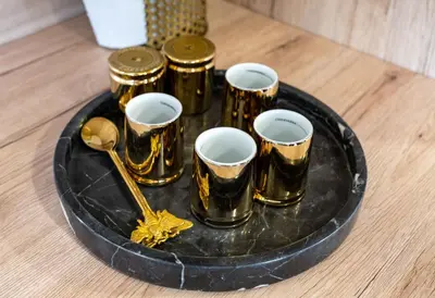 a tray with gold cups and spoons on a table at Apartment VAZATAOR with sauna in Brežice