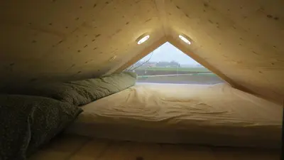 a bed in a small room with a triangular window at Apartma, glamping Na koncu vasi in Ljutomer