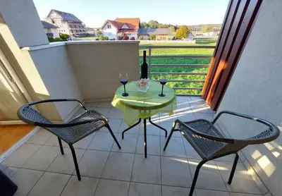 a table and two chairs on a balcony with wine glasses at Apartma TiJa in Moravske Toplice